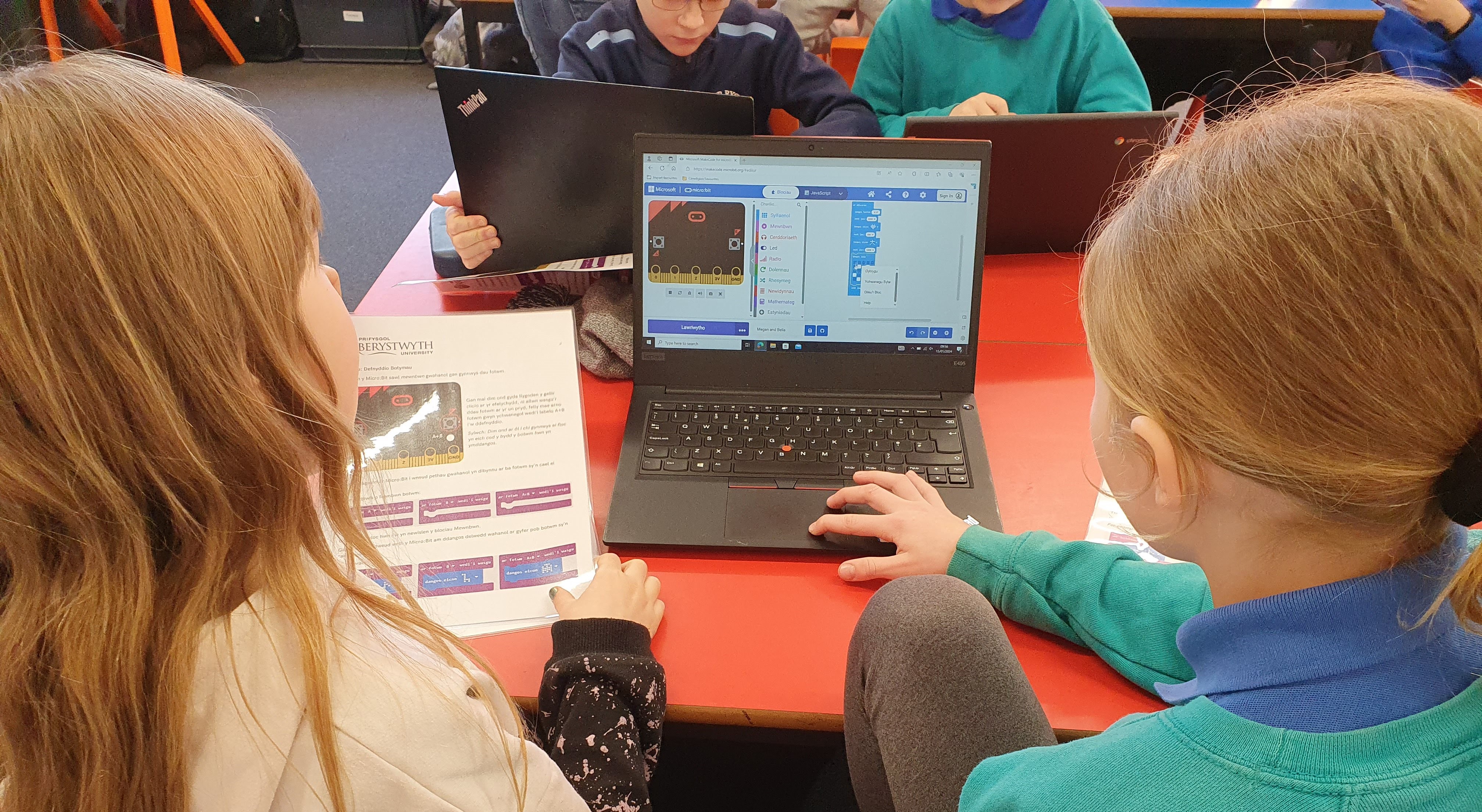 Photo over the shoulder of primary school children learning how to program